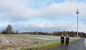 Läufer vor Funkturm am verschneiten Feld