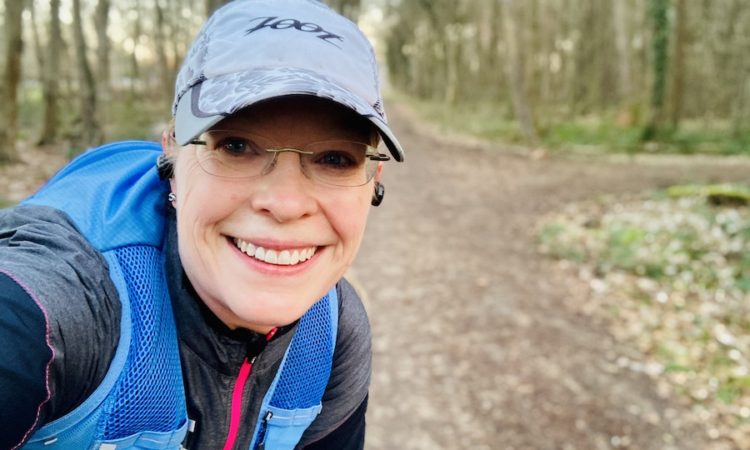 Frontalportrait von Läuferin auf einem Waldweg