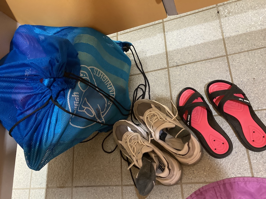 Boden der Schwimmbadumkleide mit Schuhen, Schlappen und Hilfsmittelsack
